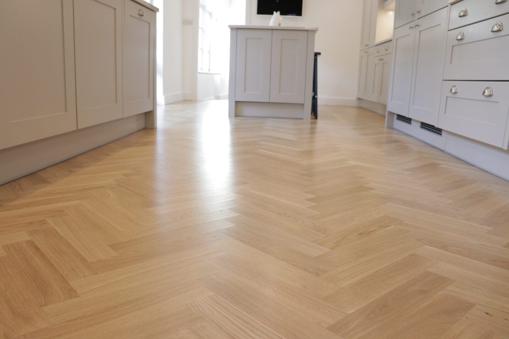 Low-angle view of a completed oak herringbone floor installation in a Cambridge kitchen.