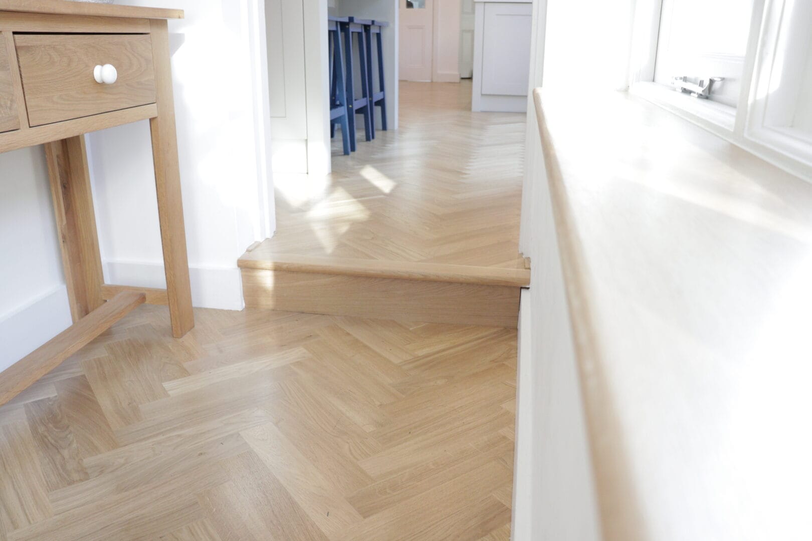 Oak herringbone flooring continuing across a doorway and raised step in Cambridge.