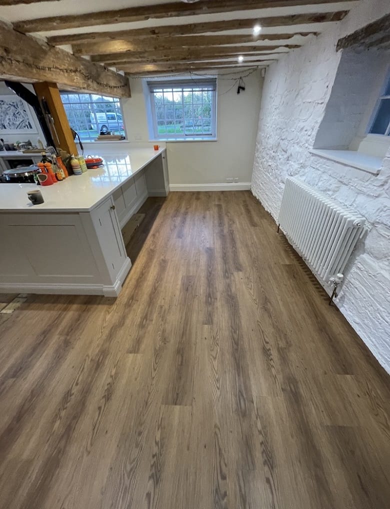 Full-length view of Cambridge kitchen with Croft Oak LVT flooring, central island and large windows overlooking the garden