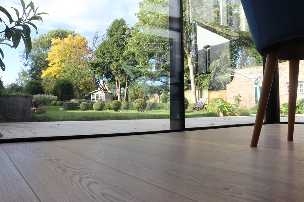 Light engineered oak flooring in Cambridge living area with bifold doors opening to landscaped garden.