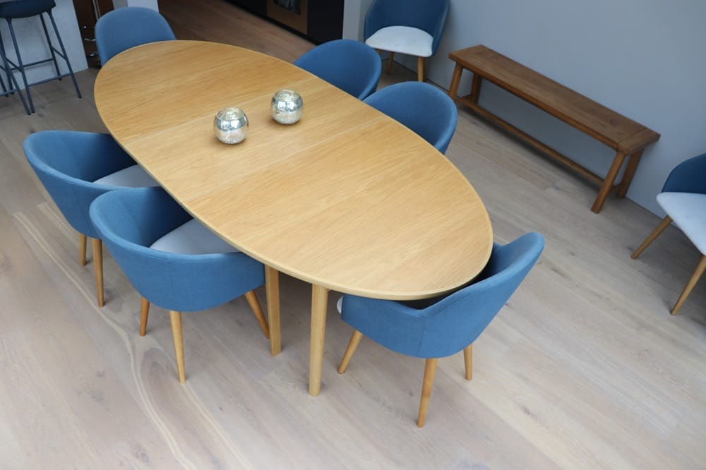Wide plank oak flooring in a Cambridge dining area with oval wooden table and bench seating.