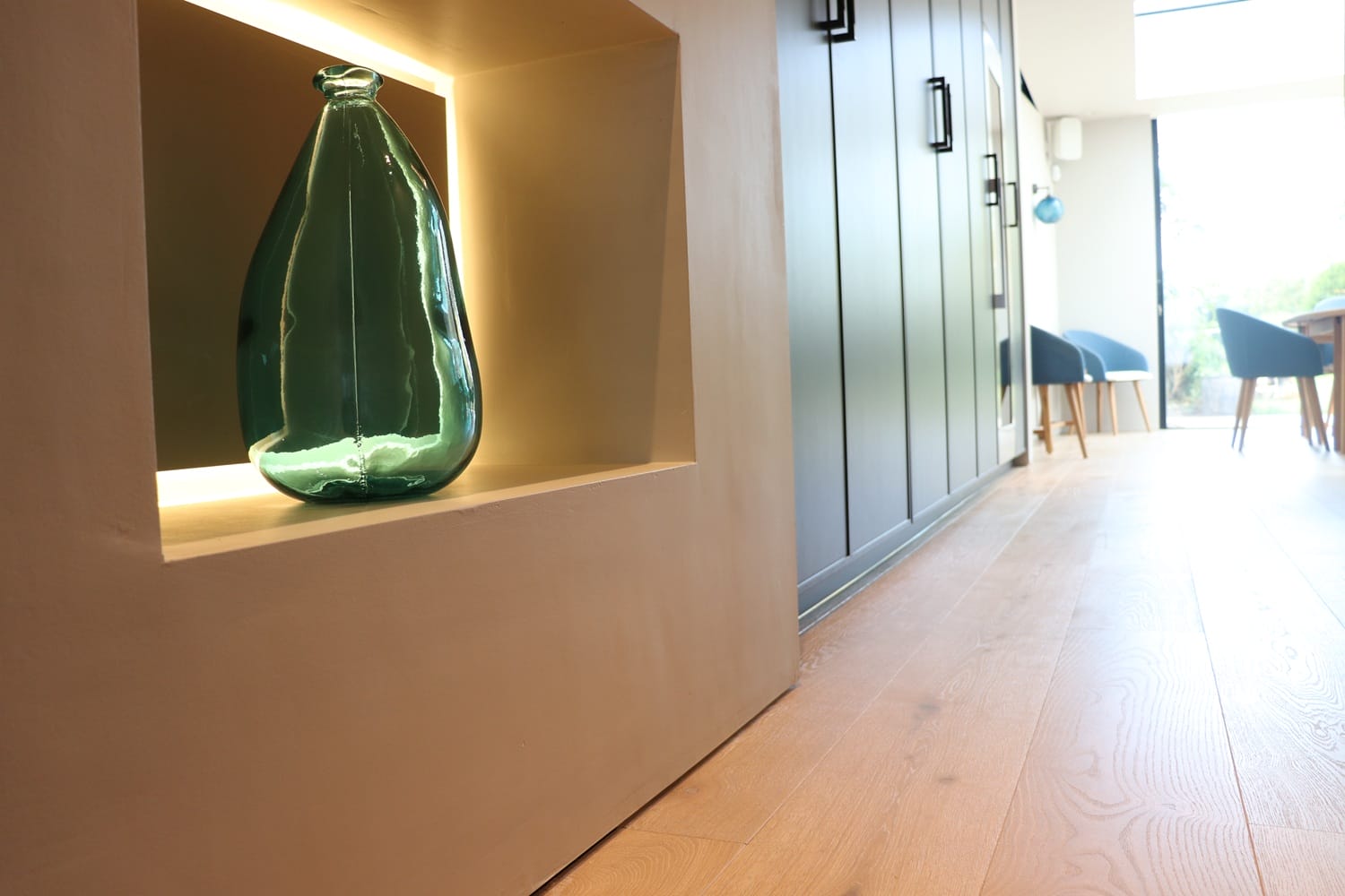 Close-up of engineered oak floor in Cambridge kitchen with built-in shelving and soft lighting detail.