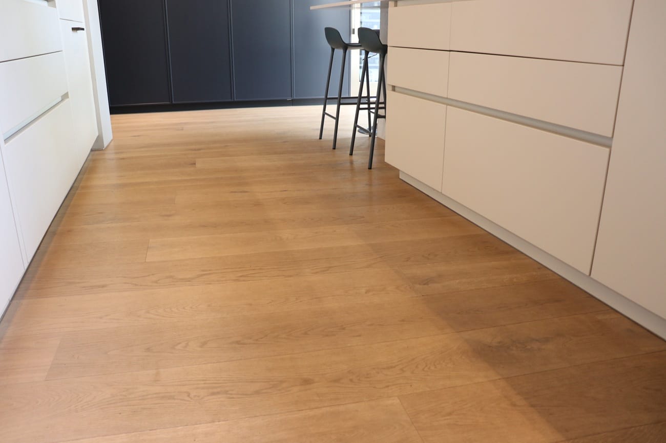 Wide plank engineered oak flooring in a modern Cambridge kitchen with dark cabinetry and breakfast bar seating.