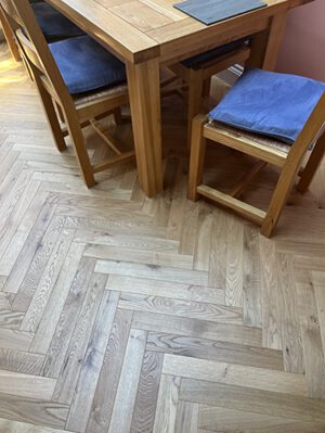 Engineered oak herringbone flooring installed beneath dining table in Cambridge home