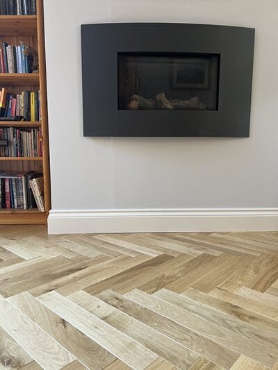 Engineered oak herringbone floor installed around modern fireplace in Cambridge