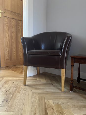 Oak herringbone flooring installed in Cambridge lounge with leather armchair