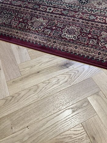Detail of oak herringbone wood flooring at rug edge in Cambridge property