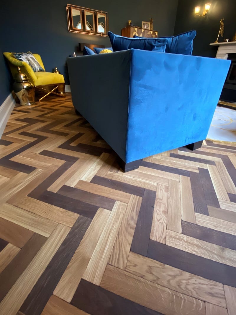 Oak basketweave parquet flooring in a Cambridge lounge with a blue sofa and dark blue walls.