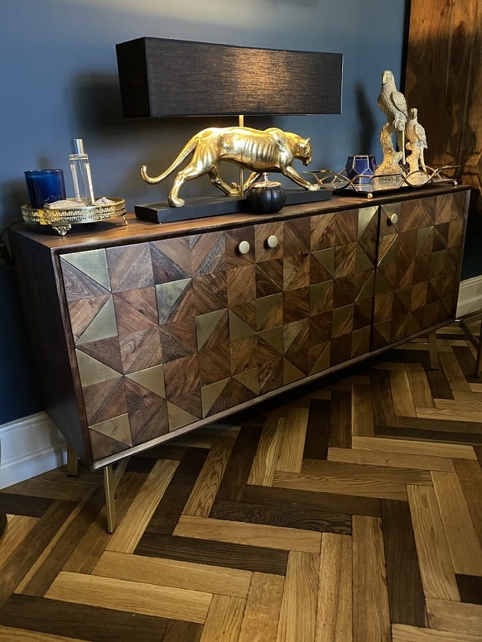 Oak basketweave parquet flooring beside a geometric wood sideboard with brass details.
