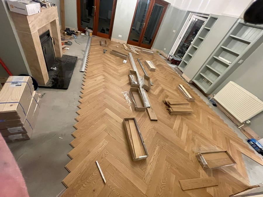 Herringbone oak floor installation in progress across the living room
