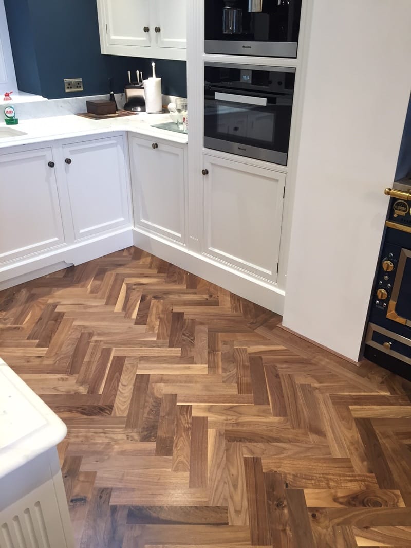 Walnut herringbone parquet floor installed around a kitchen island in a Cambridge home.