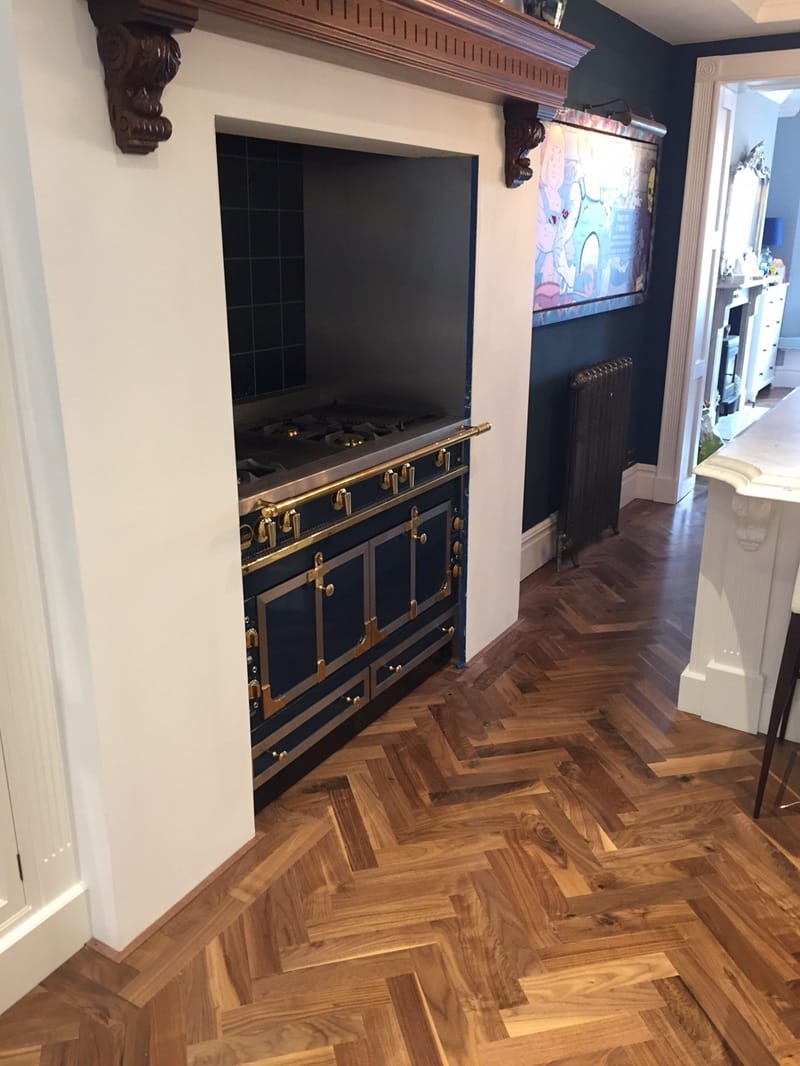 Walnut herringbone parquet floor installed near a cooking range in a Cambridge kitchen.