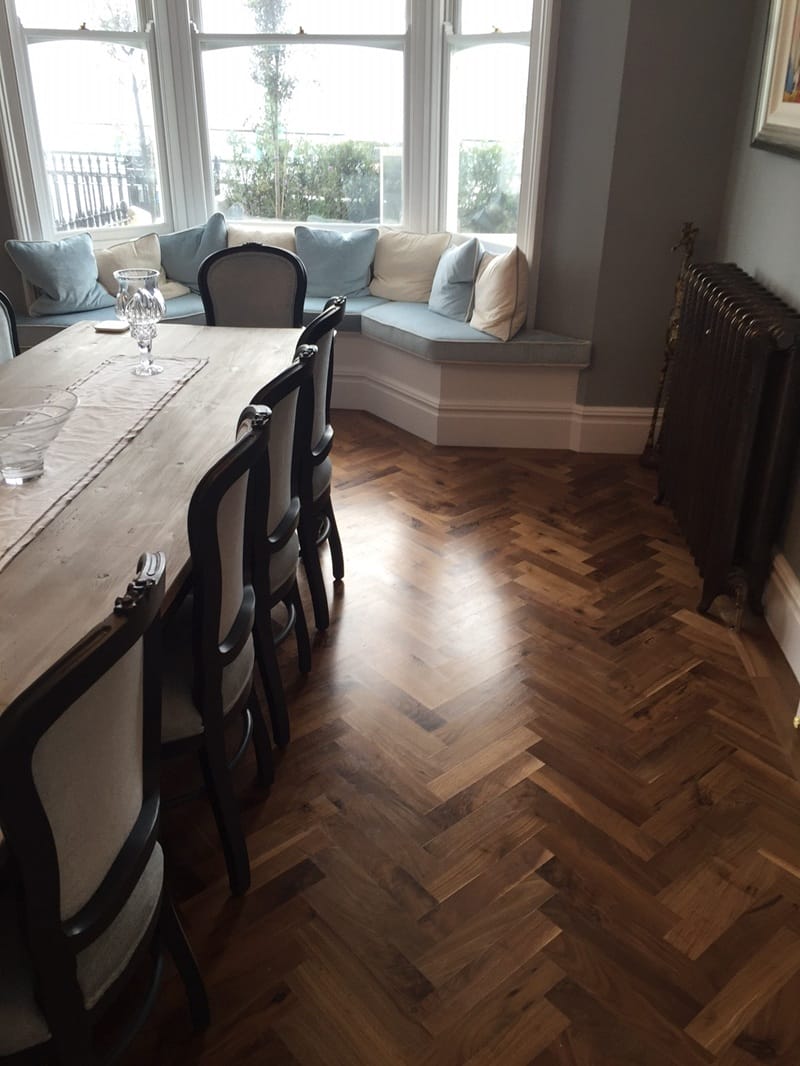 Walnut herringbone wood flooring installed beneath kitchen cabinetry in a Cambridge home.