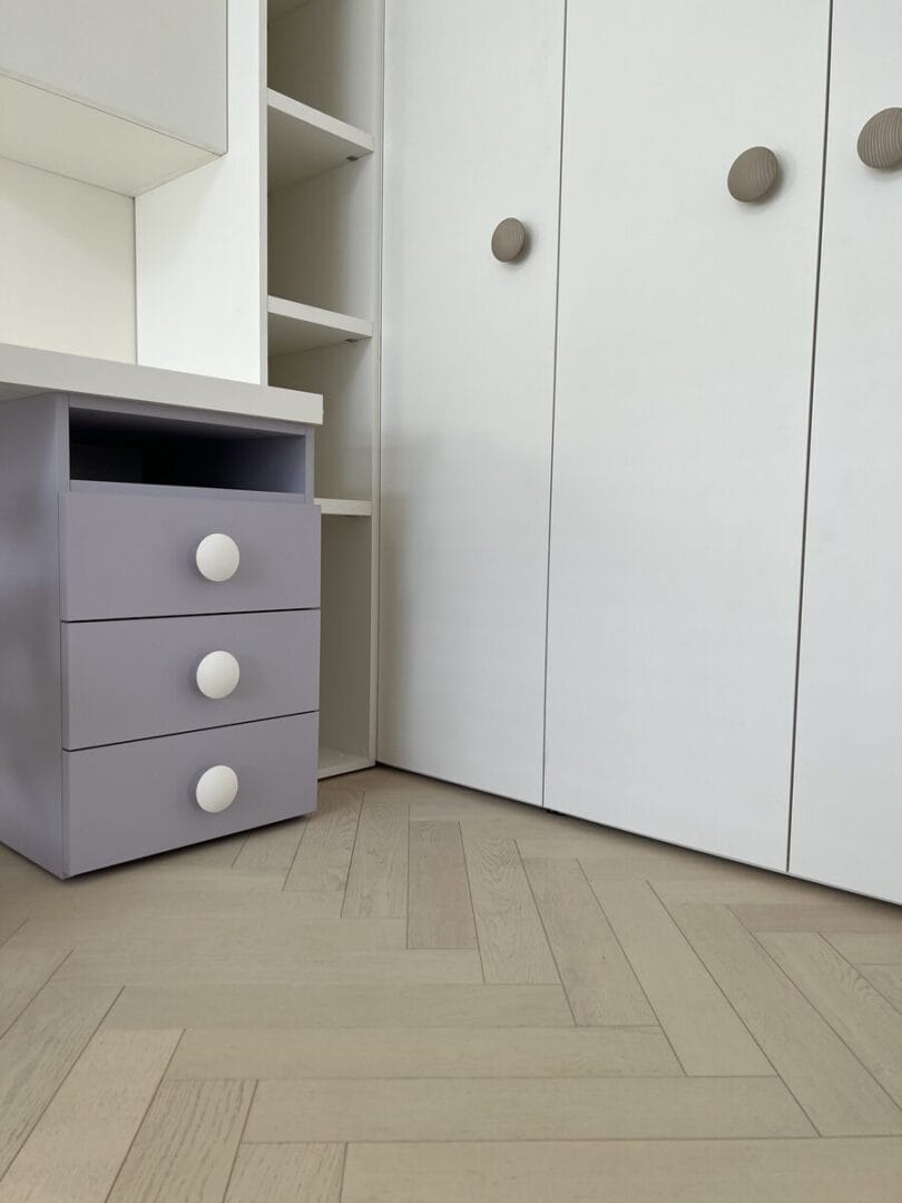 Light herringbone flooring in bedroom with white built-in wardrobes in Cambridge