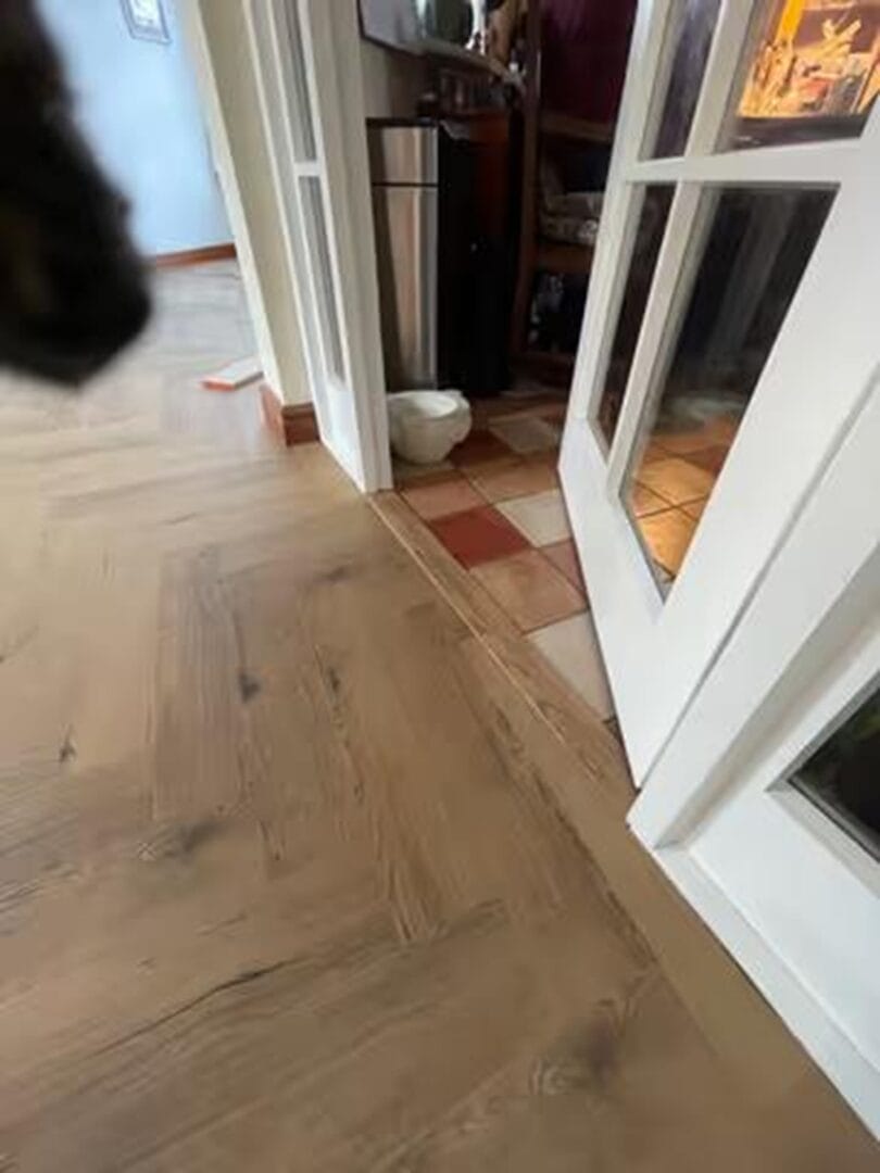 Engineered oak herringbone flooring transitioning from hallway to kitchen in Cambridge