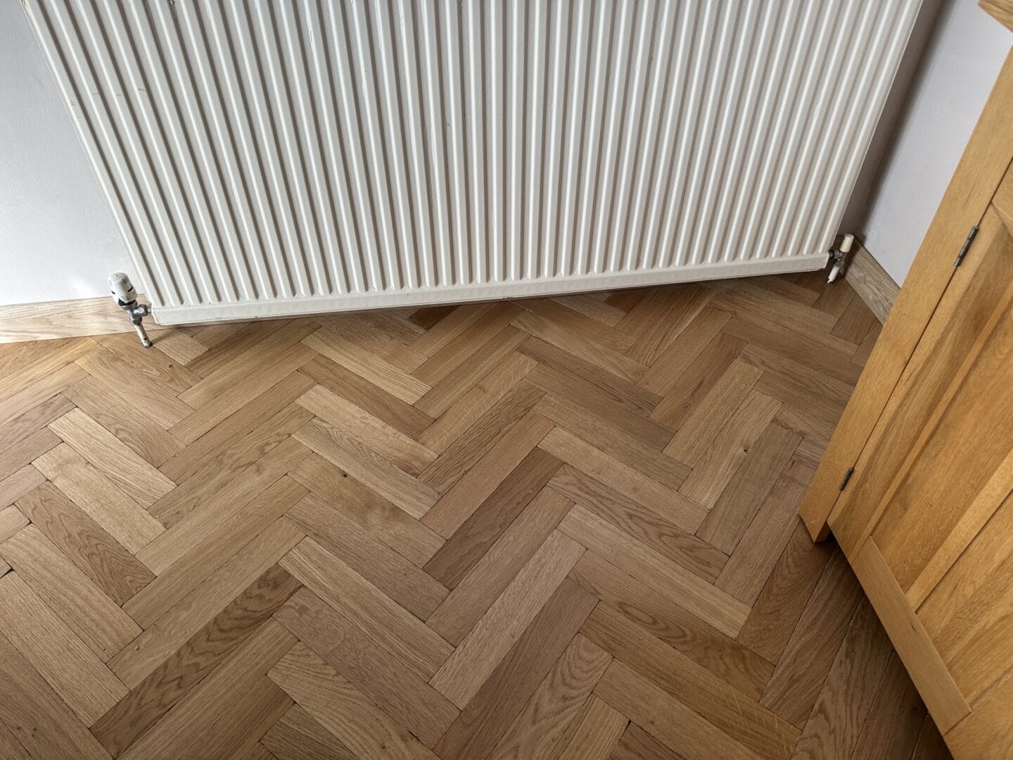 Oak herringbone flooring fitted neatly around a radiator in Cambridge