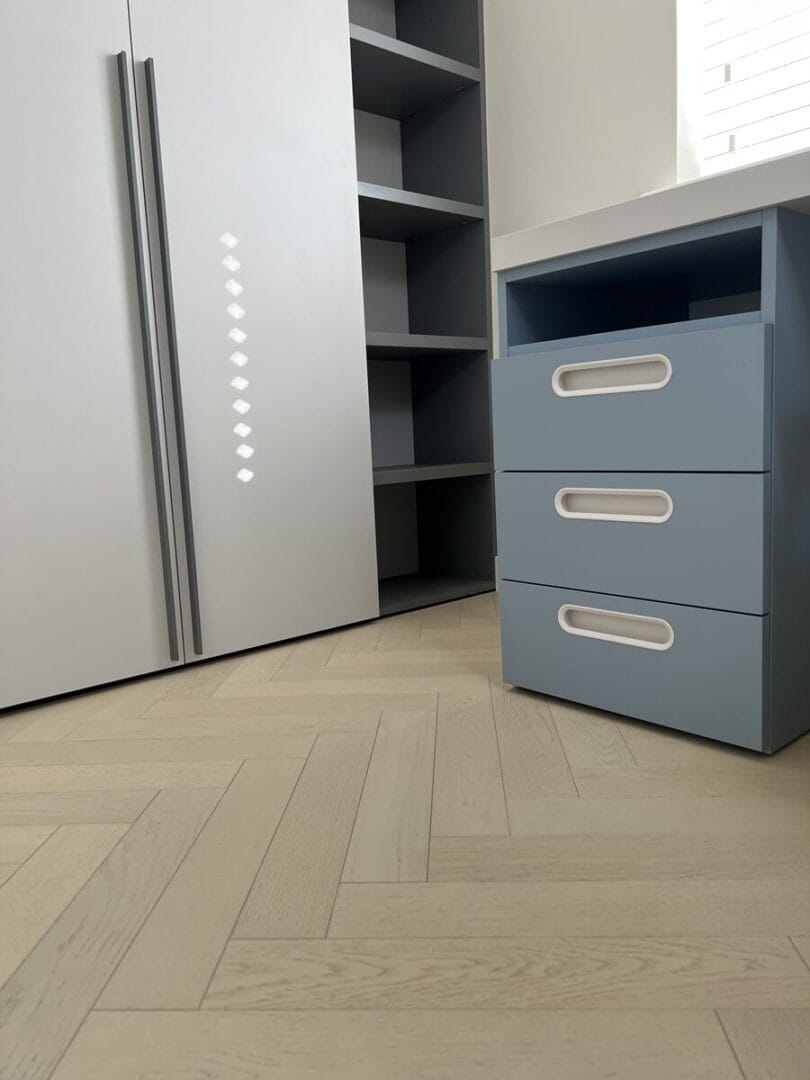 Light oak herringbone flooring in bedroom with built-in storage units in Cambridge