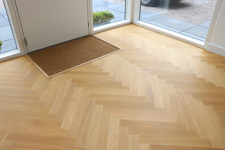 Oak herringbone flooring at front entrance with door mat in Cambridge home