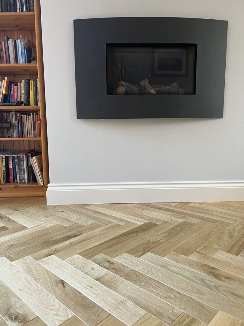 Engineered oak herringbone flooring in living room with wall-mounted fireplace in Cambridge