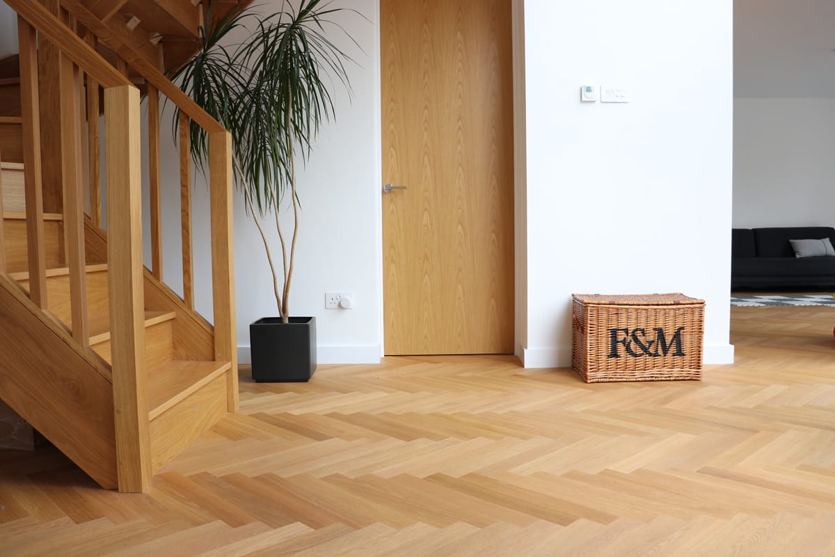 Oak herringbone flooring in open-plan space with staircase and plant in Cambridge