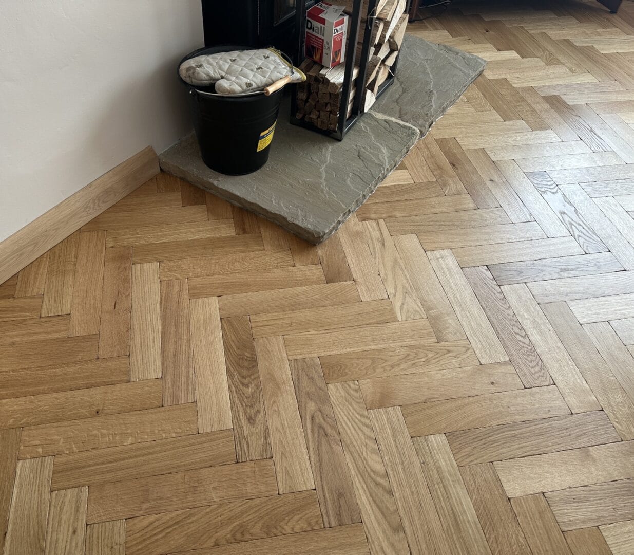 Oak herringbone flooring installed around fireplace hearth in Cambridge