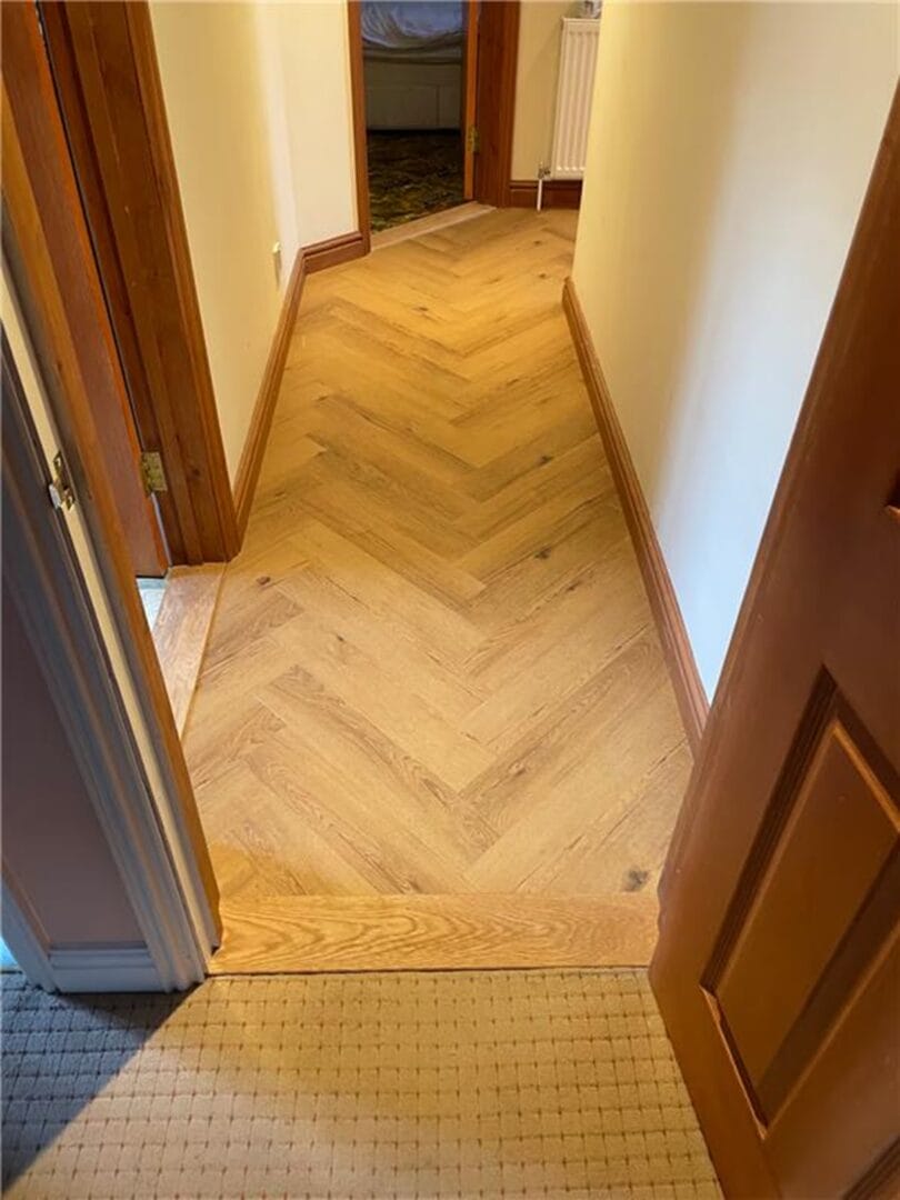 Oak herringbone flooring with stepped transition between rooms in Cambridge