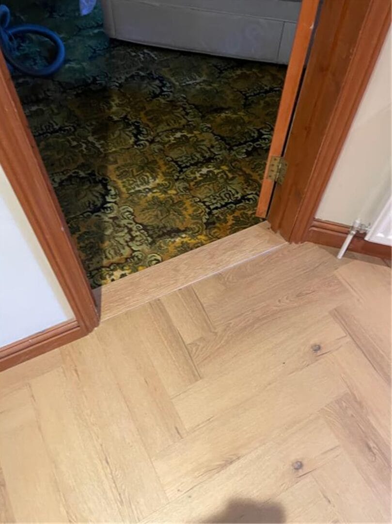 Oak herringbone flooring meeting carpet with threshold strip in Cambridge