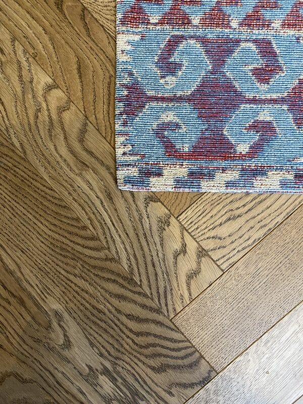 Dark oak herringbone wood flooring beside a patterned rug in a Cambridge home