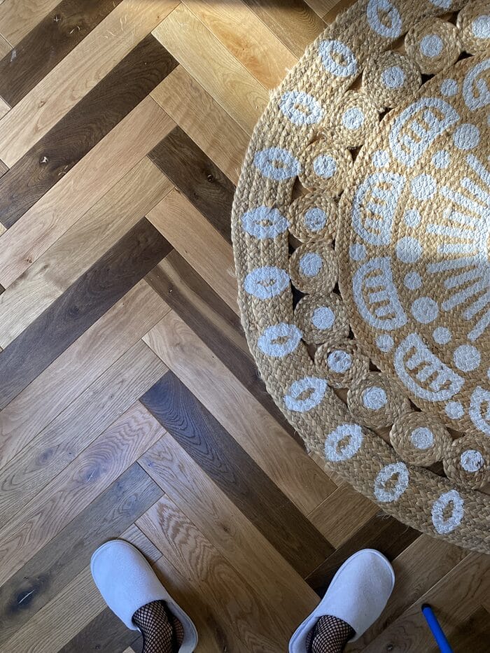 Detailed view of oak herringbone flooring next to a textured rug in Cambridge home