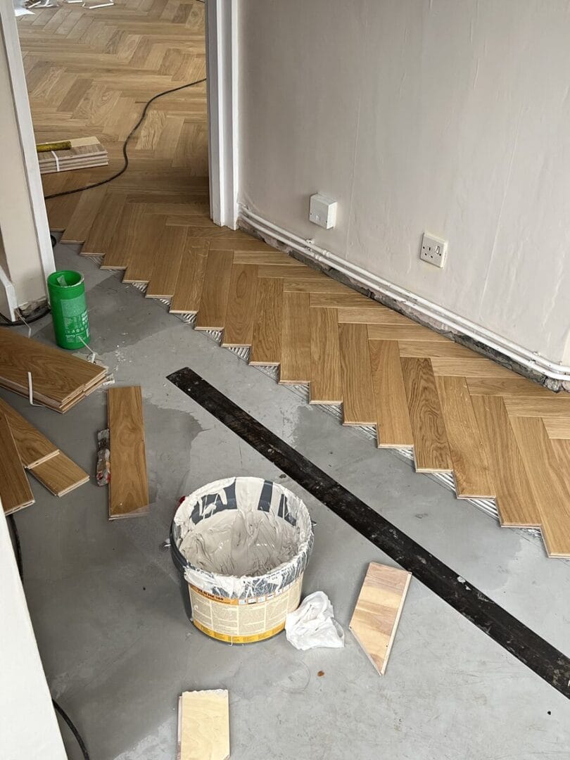 Engineered oak herringbone flooring being fitted around a hallway in Cambridge.