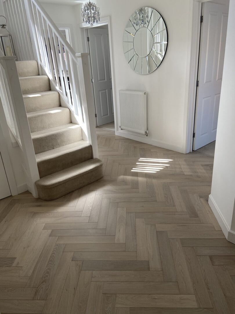 Light oak herringbone flooring installed throughout a bright hallway in Cambridge.