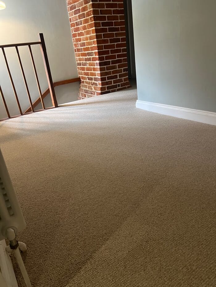 Natural loop carpet fitted on a period cottage landing in Cambridge, with exposed brickwork and grey walls.