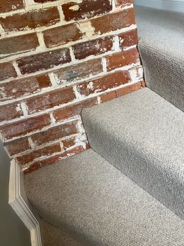 Natural loop carpet fitted on cottage stairs beside exposed brickwork in Cambridge.