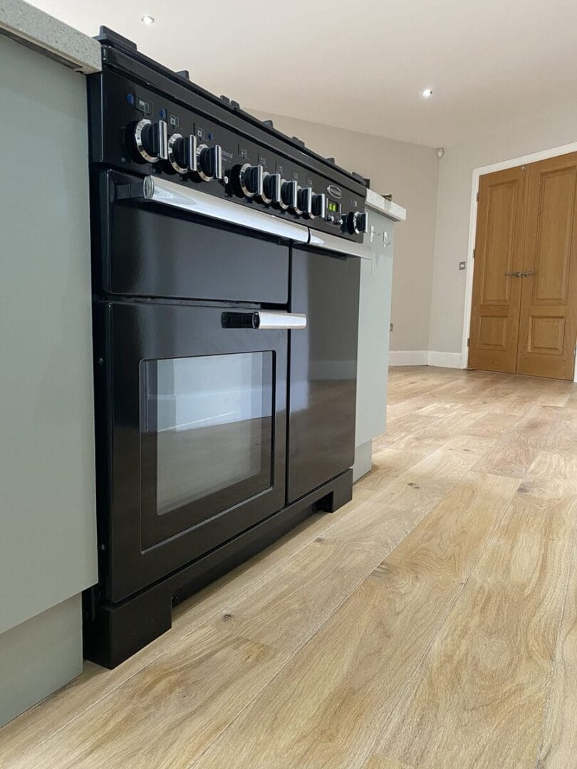 Black range cooker on newly finished oak floor in a Cambridge kitchen