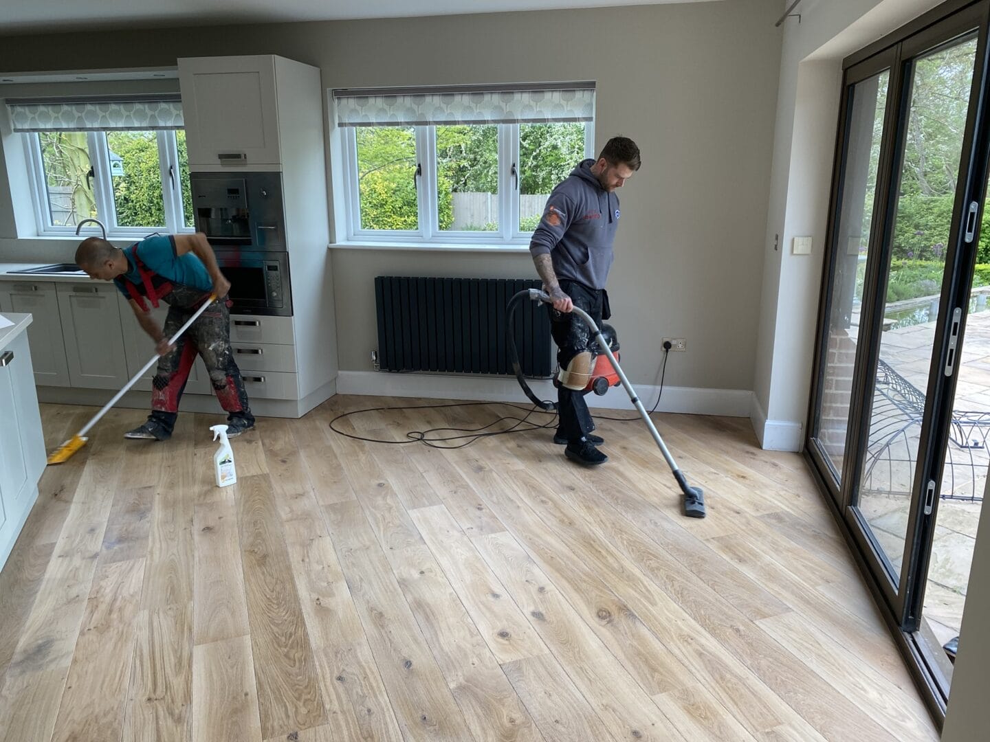 Team cleaning after oak floor sanding and finishing in Cambridge kitchen
