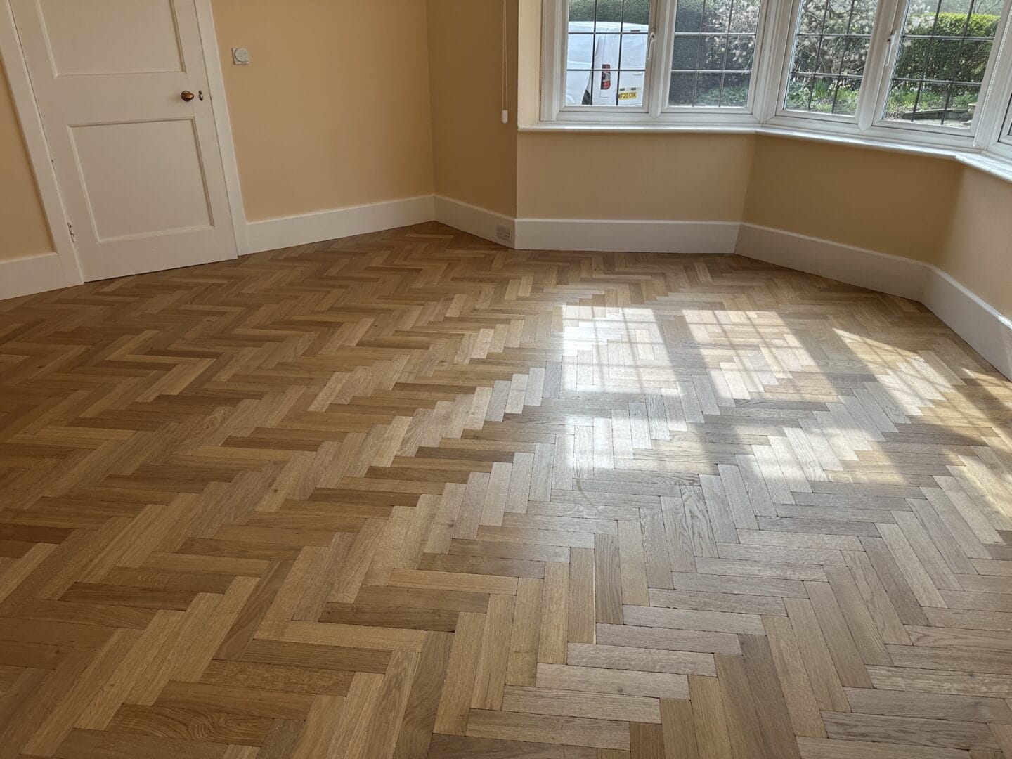 Engineered oak parquet flooring installed around a curved bay window area
