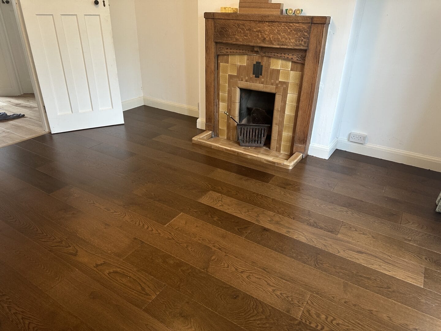 Completed walnut engineered flooring surrounding a traditional fireplace in Cambridge