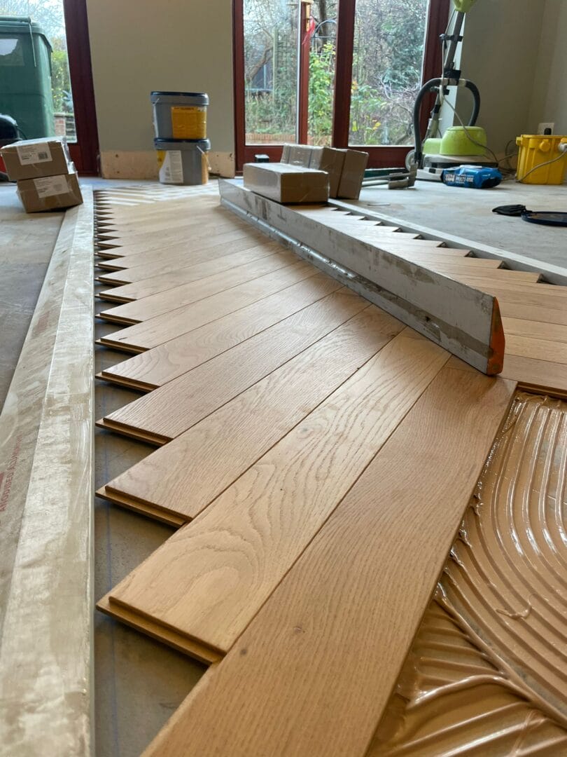Engineered oak parquet boards being aligned during a flooring installation in Cambridge.