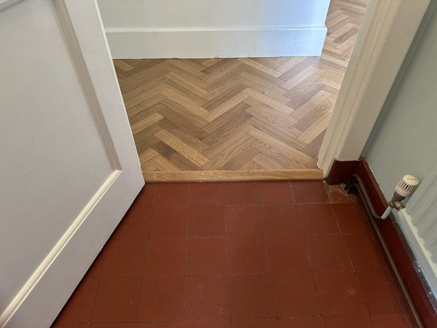 Engineered oak herringbone flooring with threshold transition from original red quarry tiles in a Sevenoaks home