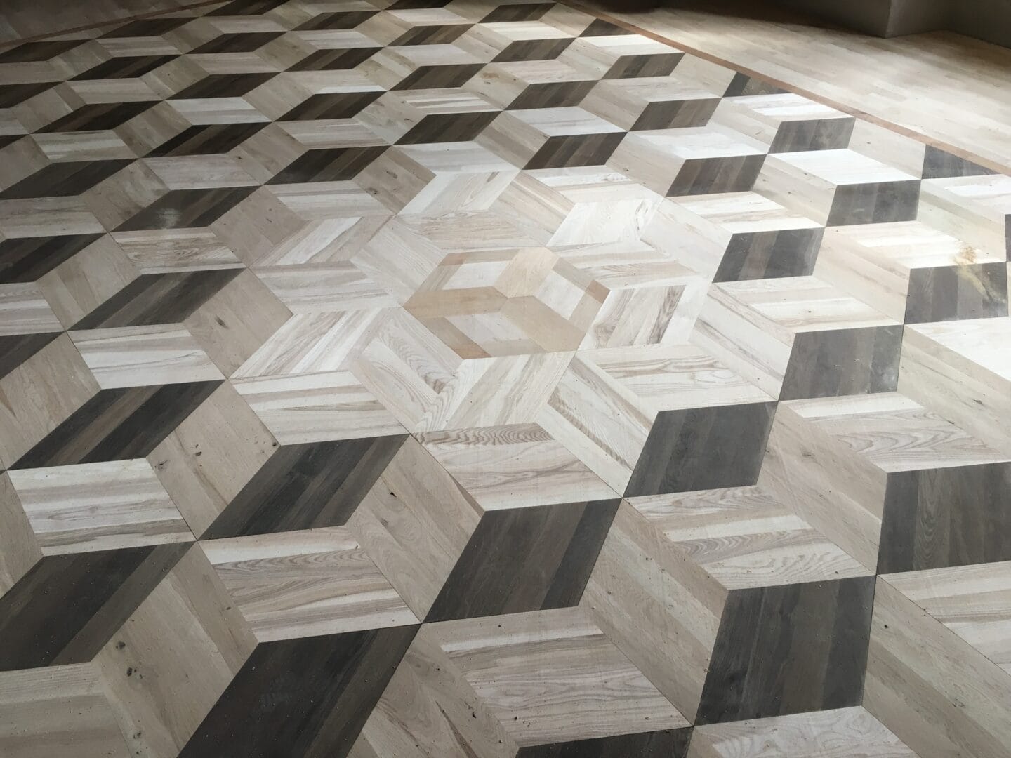 Three-dimensional cube parquet flooring pattern laid in contrasting wood tones.