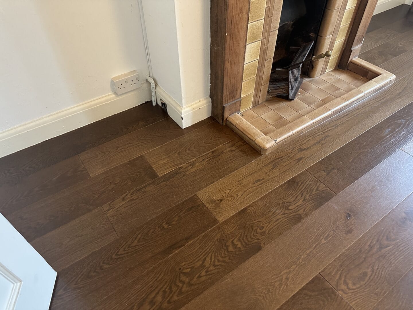 Walnut engineered flooring installed neatly around a tiled fireplace in a Cambridge home