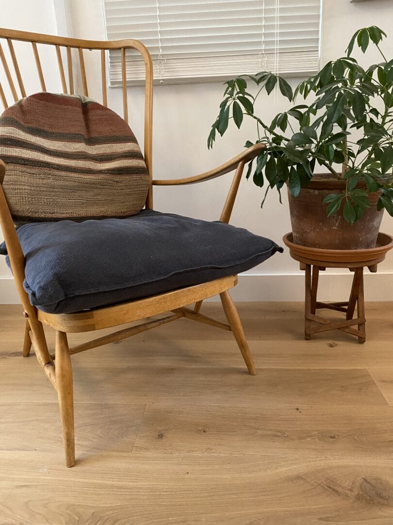 Ash engineered wood floor beneath a vintage spindle-back armchair with a potted plant