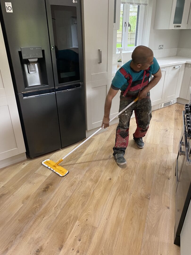 Technician mopping a newly fitted ash engineered wood floor in a Cambridge kitchen