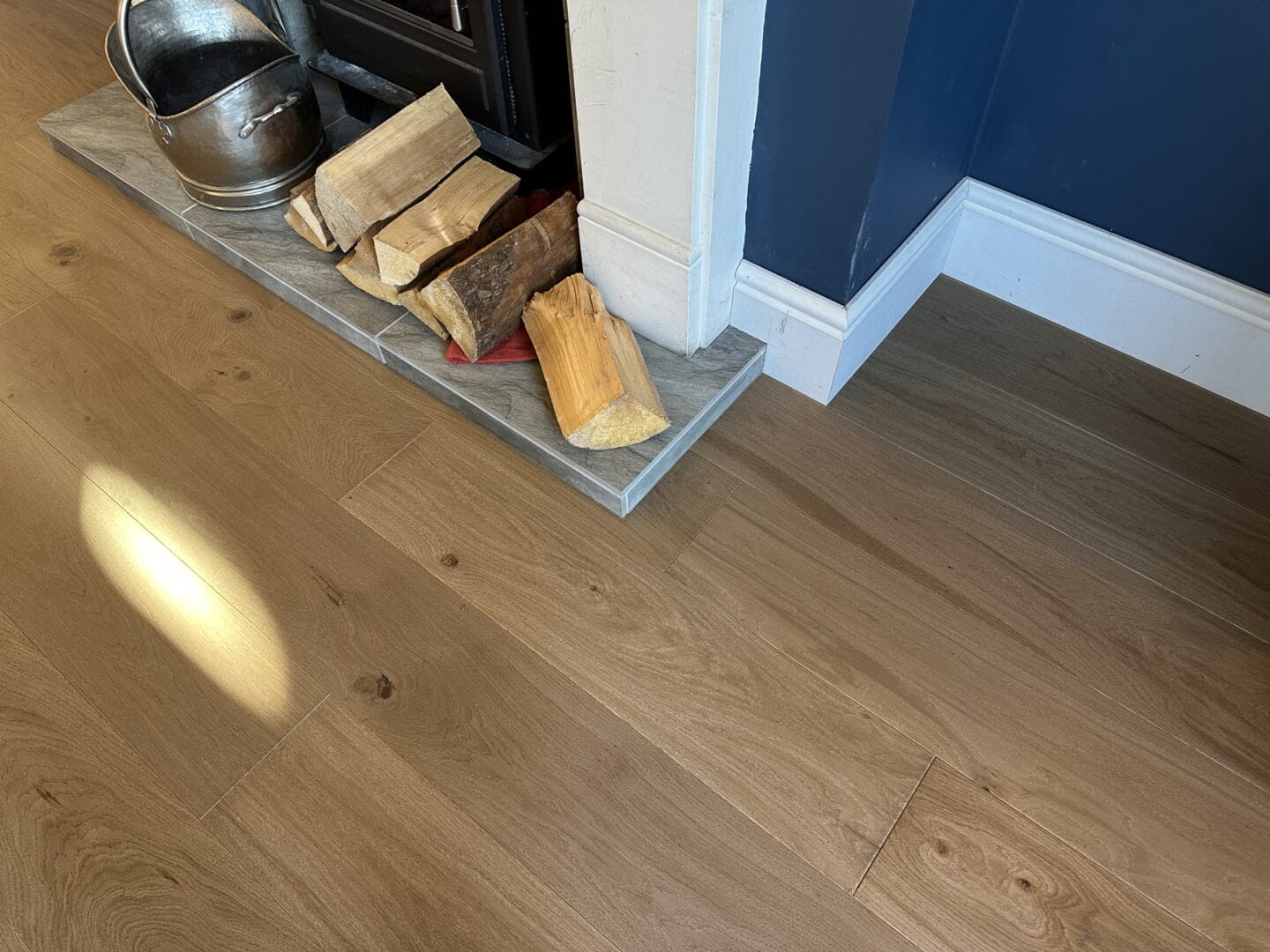 Maple engineered wood flooring fitted around a wood-burning stove in Cambridge