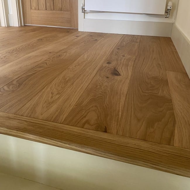 Close-up of engineered oak flooring meeting a carpeted room at a wooden threshold strip in a Waterbeach home