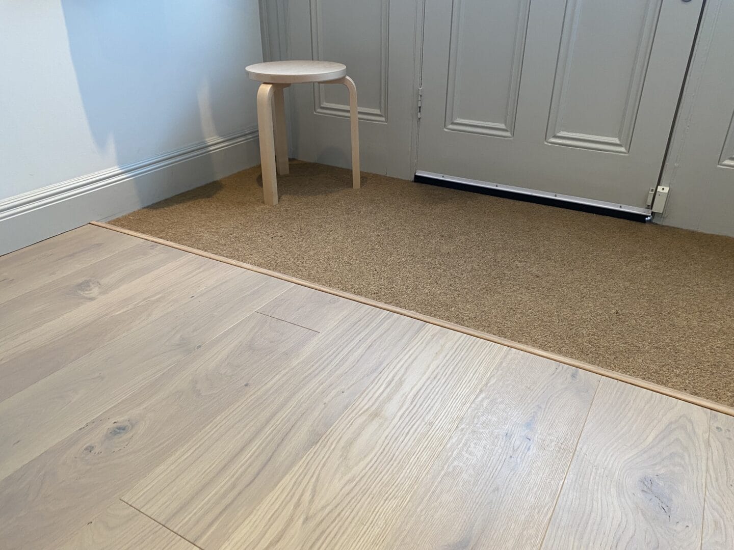 Engineered wood flooring meeting a carpeted room at a doorway threshold