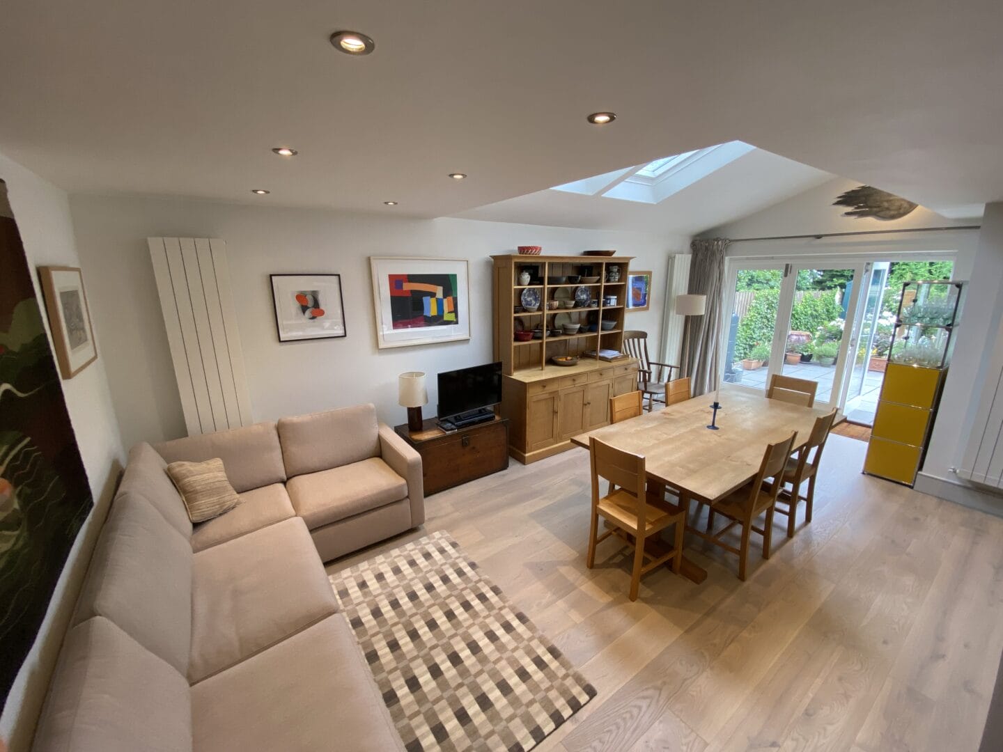 Engineered wood flooring throughout an open-plan living and dining room with a skylight and garden doors