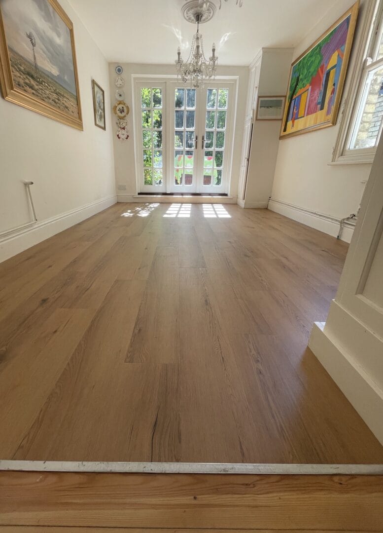 Engineered wood flooring in a period-style dining room with French doors and artwork