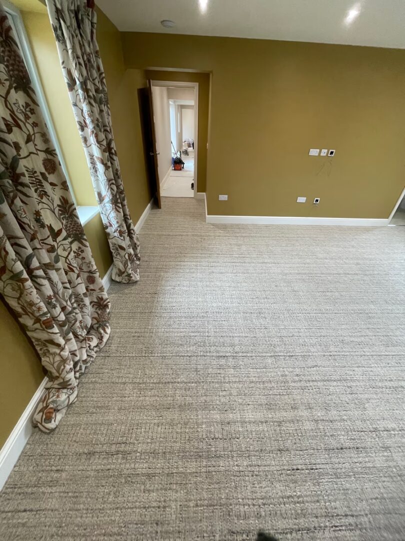 The finished snug in a barn conversion extension, with beige woven carpet, mustard walls and a built-in navy bookcase, ready for furniture.