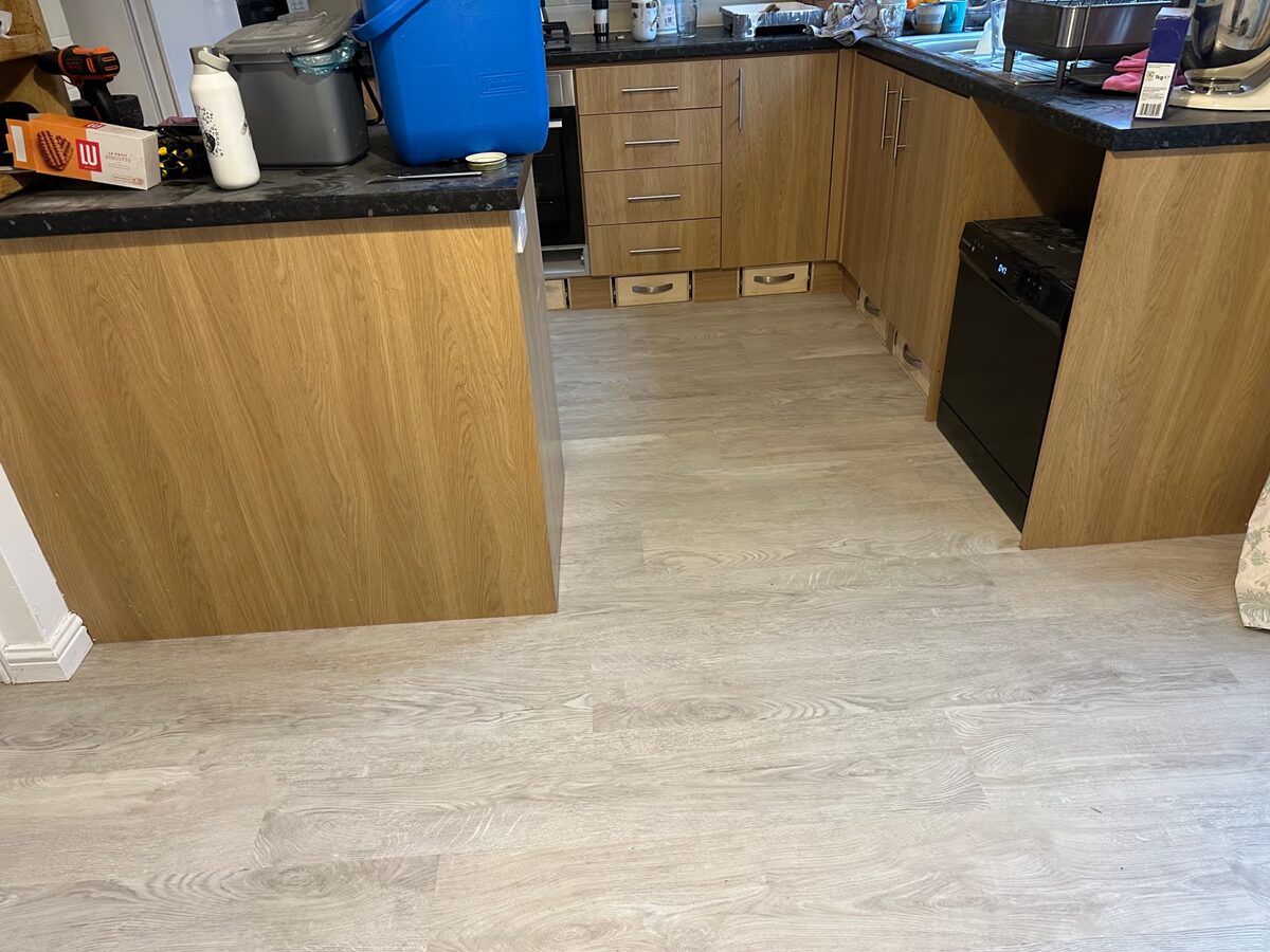 Harvey Maria White Oak flooring fitted through a U-shaped kitchen with oak-effect units and dark worktops